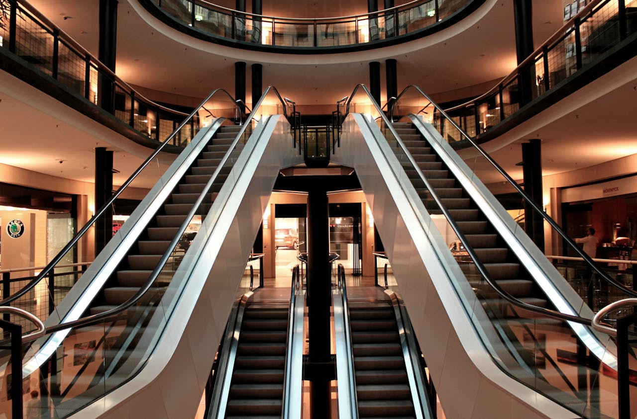 about-us Symmetrical view of escalators in a modern shopping mall interior, showcasing architecture and design.