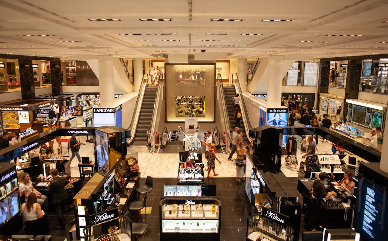 heros-img A bustling scene inside a modern shopping mall with escalators and various retail stalls.
